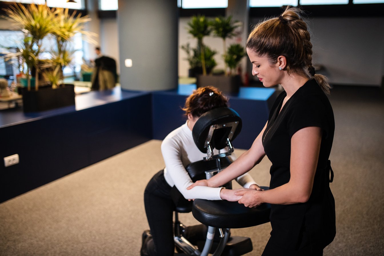 Massage therapist massaging business people in their office on a portable massage chair